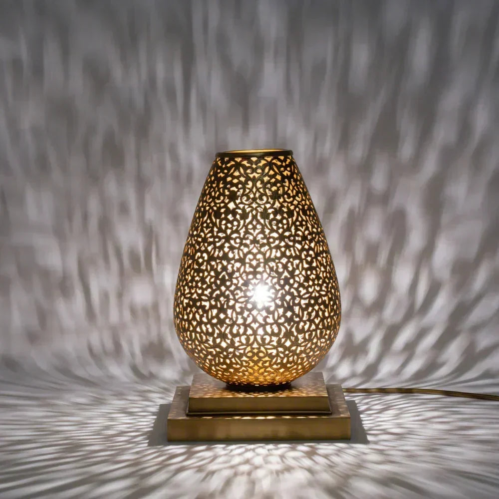 Decorative table lamp with intricate design casting shadows on a textured wall.