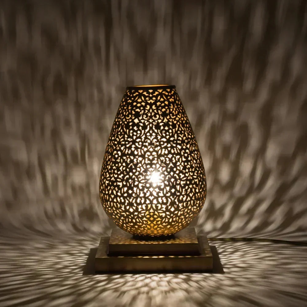 Decorative lamp with intricate design casting shadows on a textured wall.