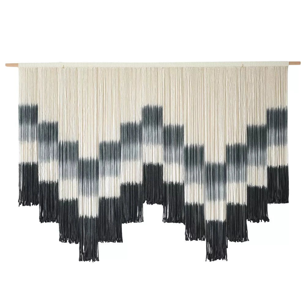 Black and white patterned wall art with fringe on a white background