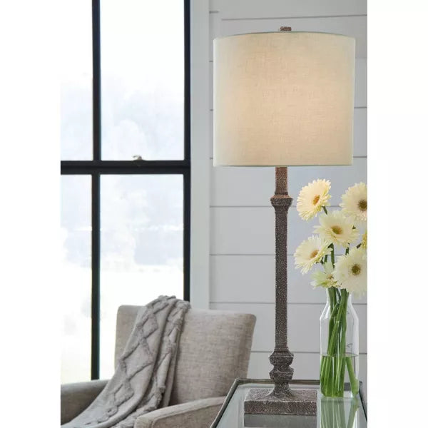 Table lamp with a textured base and beige shade on a white background