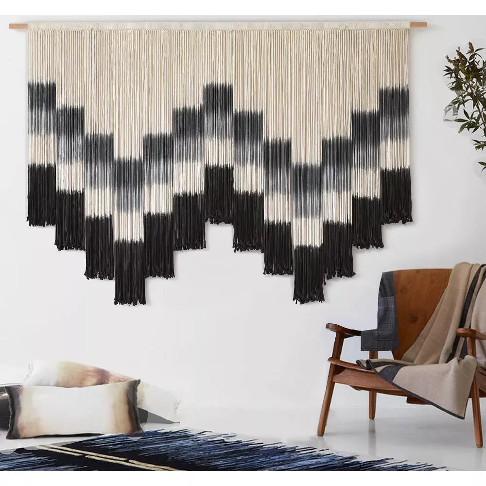 Black and white patterned wall art with fringe on a white background