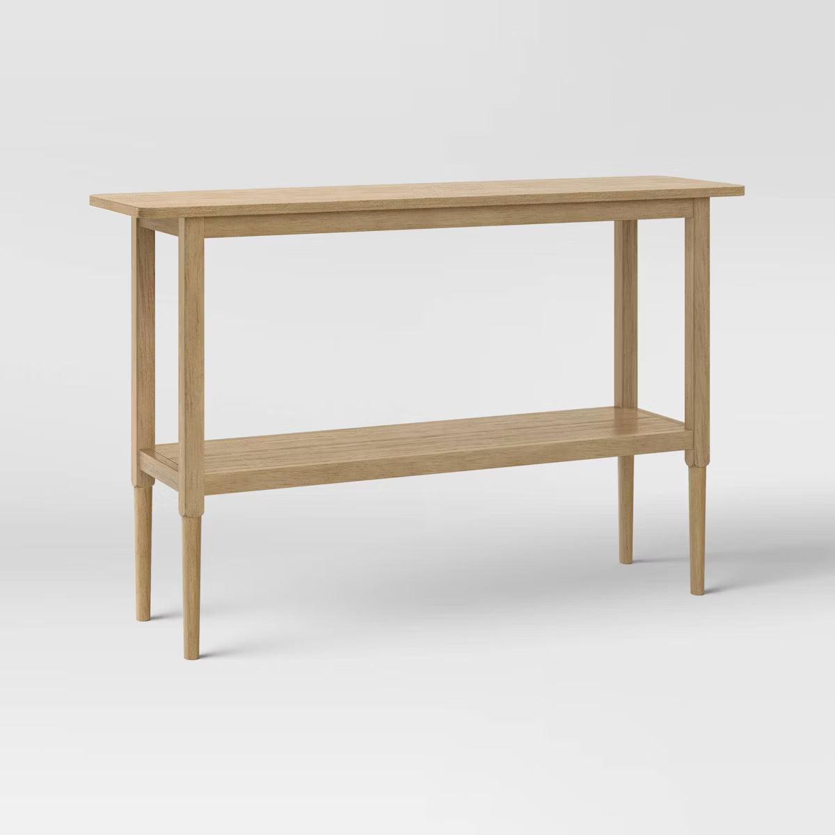 A light brown colored rectangular table with four slender legs and a lower shelf.