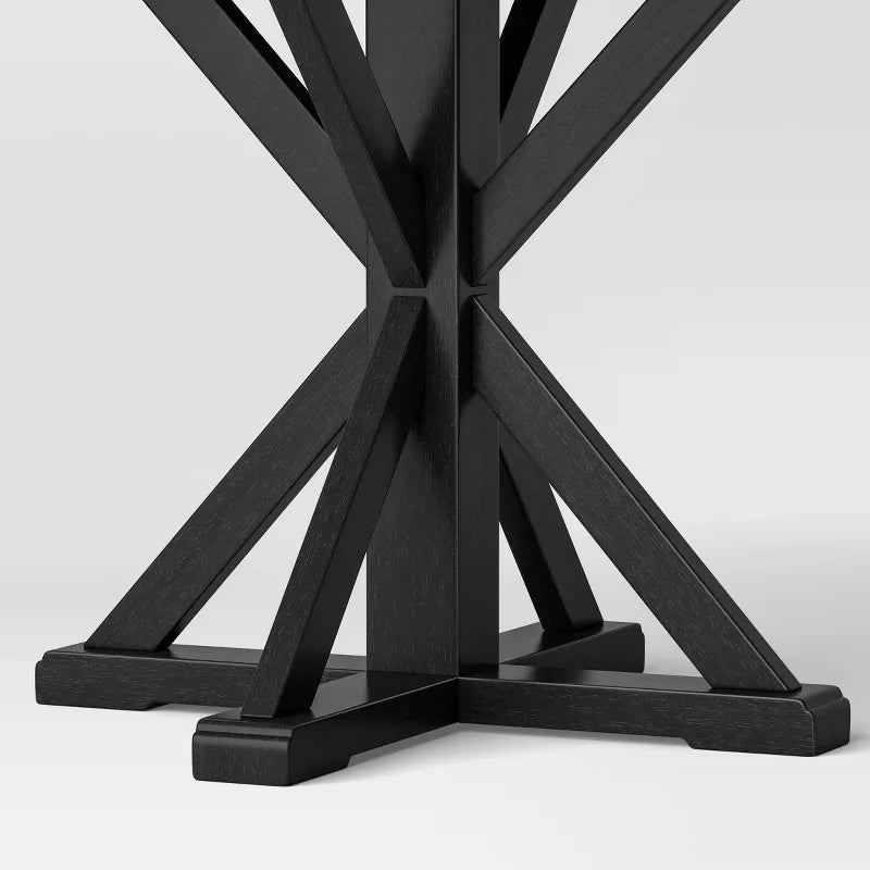 Black round table with a X-shaped base on a white background
