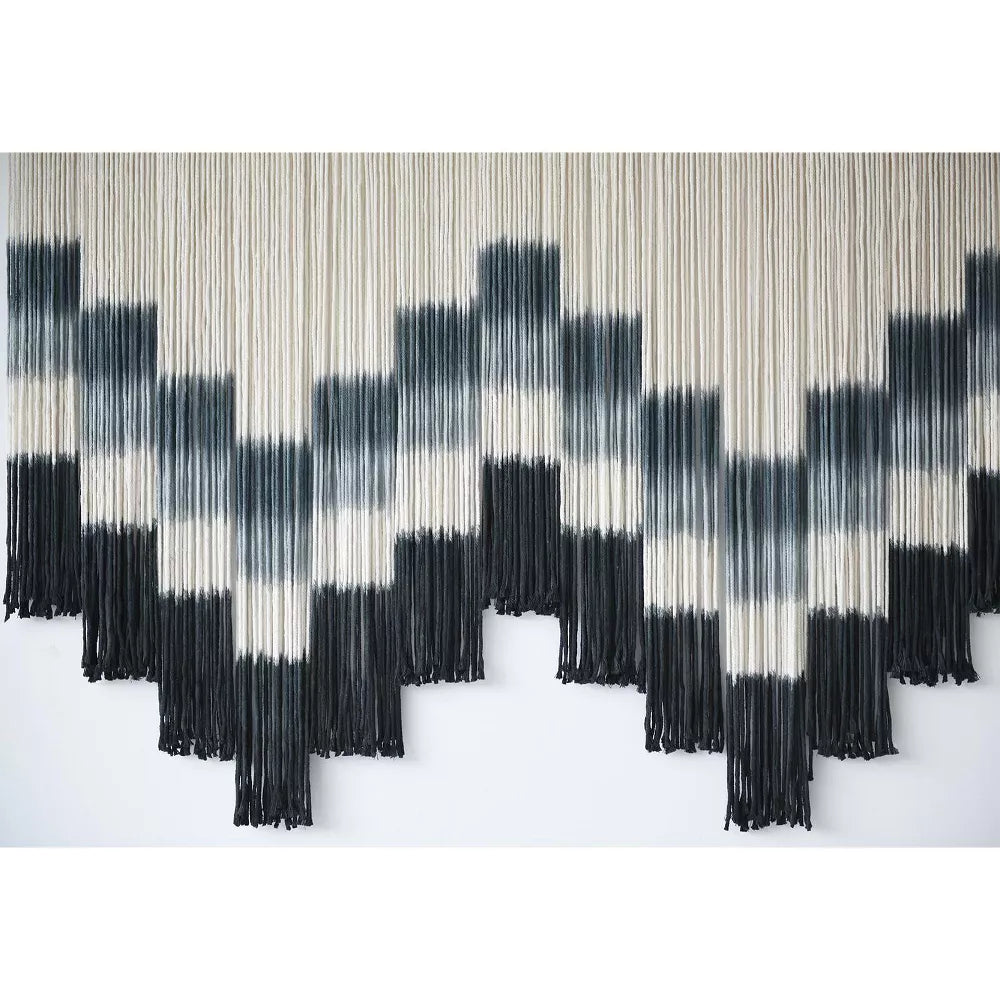 Black and white patterned wall art with fringe on a white background