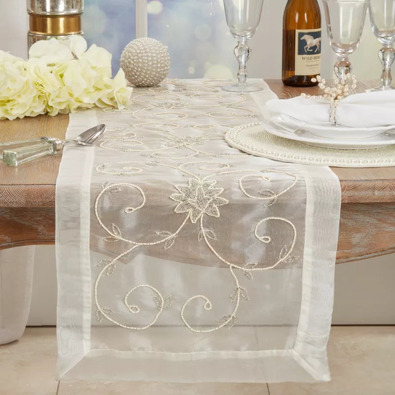 Decorative table runner with floral embroidery on a set dining table.