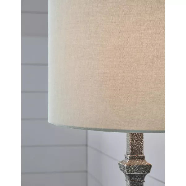 Table lamp with a textured base and beige shade on a white background