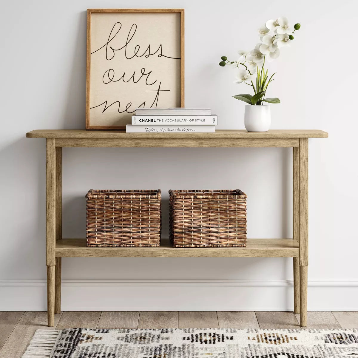 A light brown colored rectangular table with four slender legs and a lower shelf.