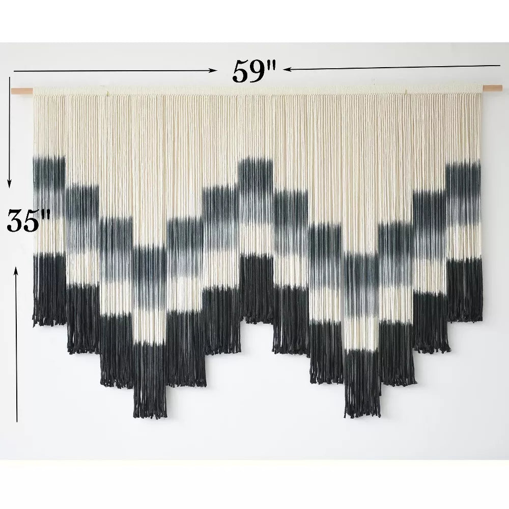 Black and white patterned wall art with fringe on a white background