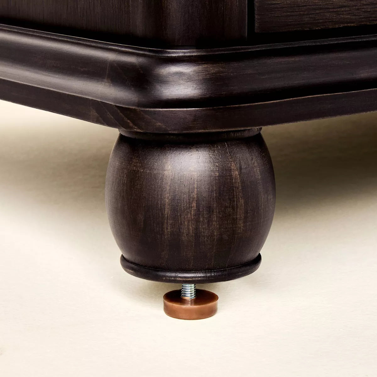 A dark brown colored dresser with six drawers, featuring round knobs, is adorned with a white lamp, books, a bowl, and a candle holder on top Black.