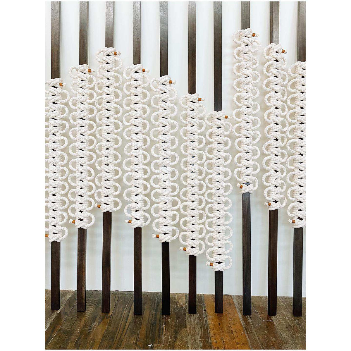 Decorative screen with wavy white design on a wooden floor and striped wall background