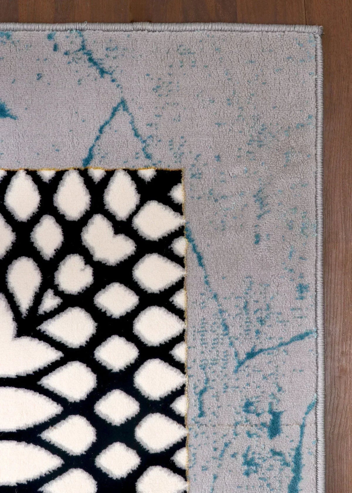 Close-up of a rug with geometric patterns on a wooden floor.