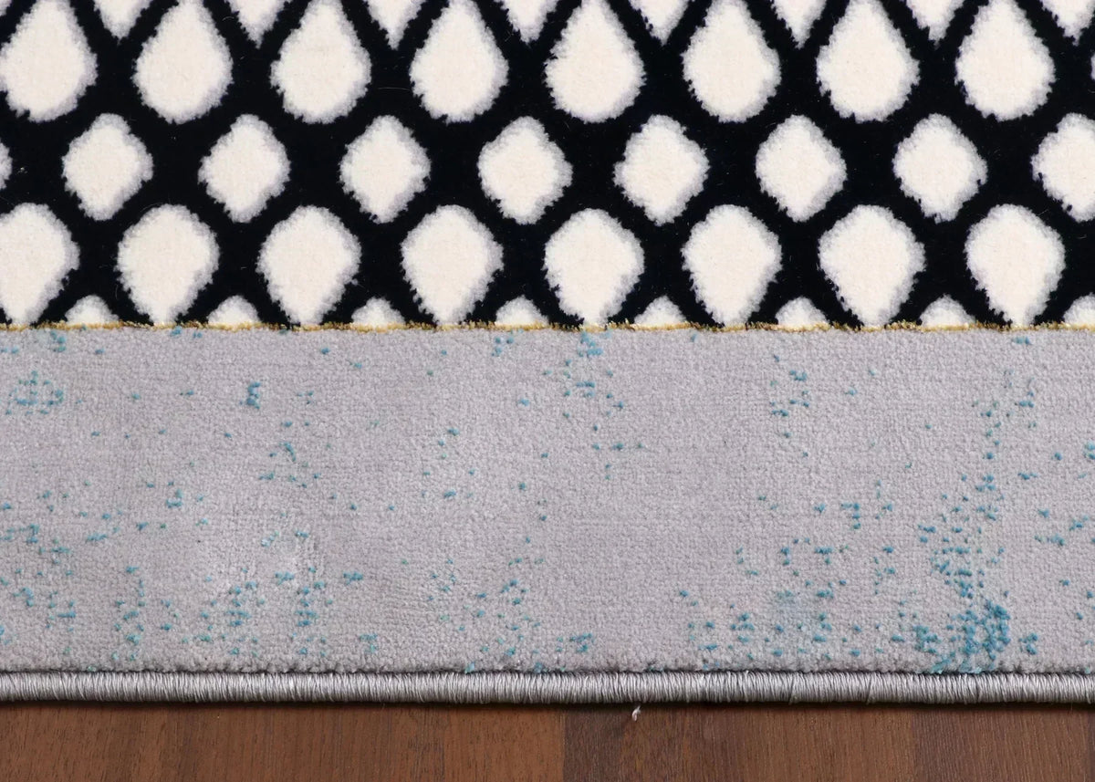 Close-up of a rug with geometric patterns on a wooden floor.