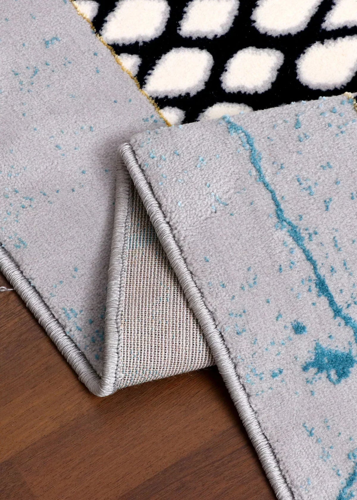 Close-up of a rug with geometric patterns on a wooden floor.