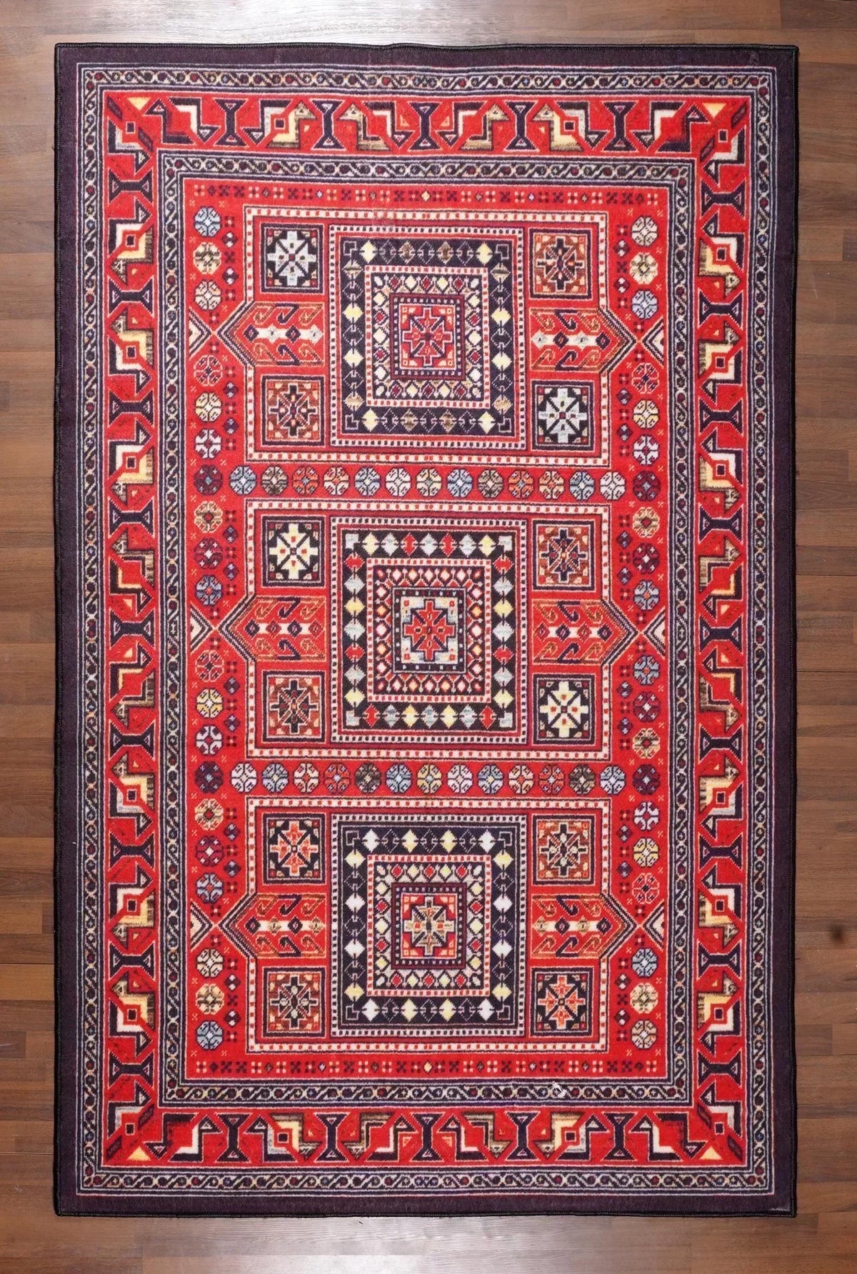 Close-up of a red and black patterned rug on a wooden floor.
