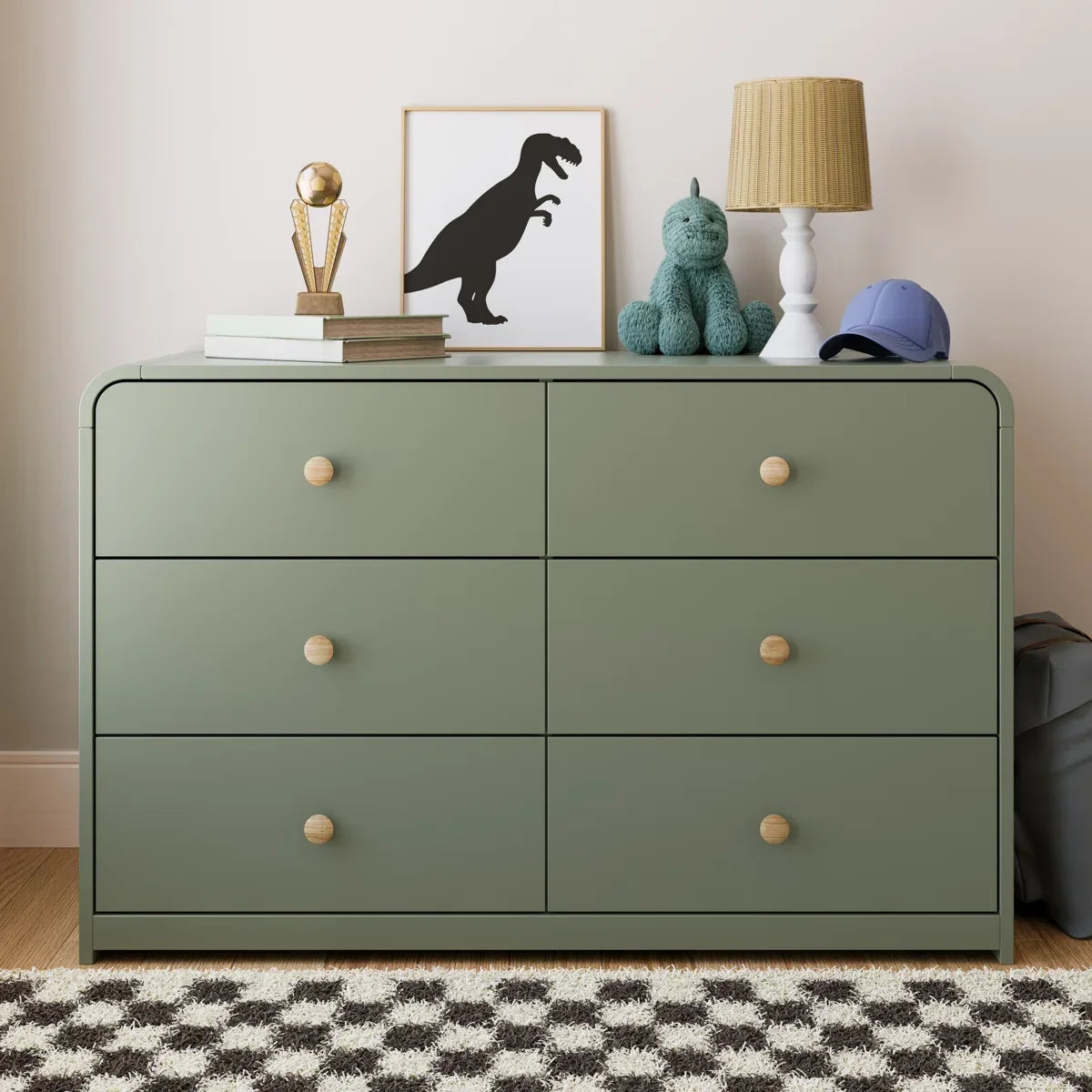 A modern six-drawer dresser in a muted sage green with small round light wood knobs, shown against a neutral beige background.
