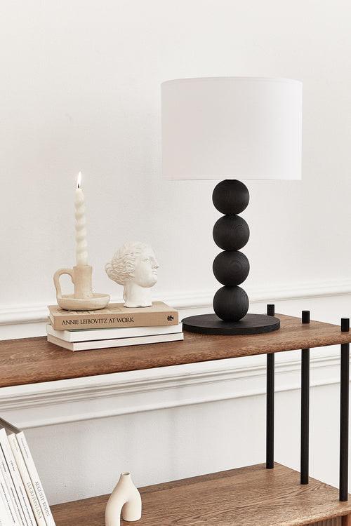 Table lamp with a white shade and black cylindrical base on a light gray background