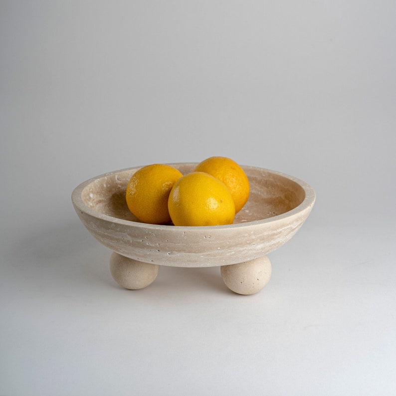 Ceramic bowl with three lemons on a light gray background