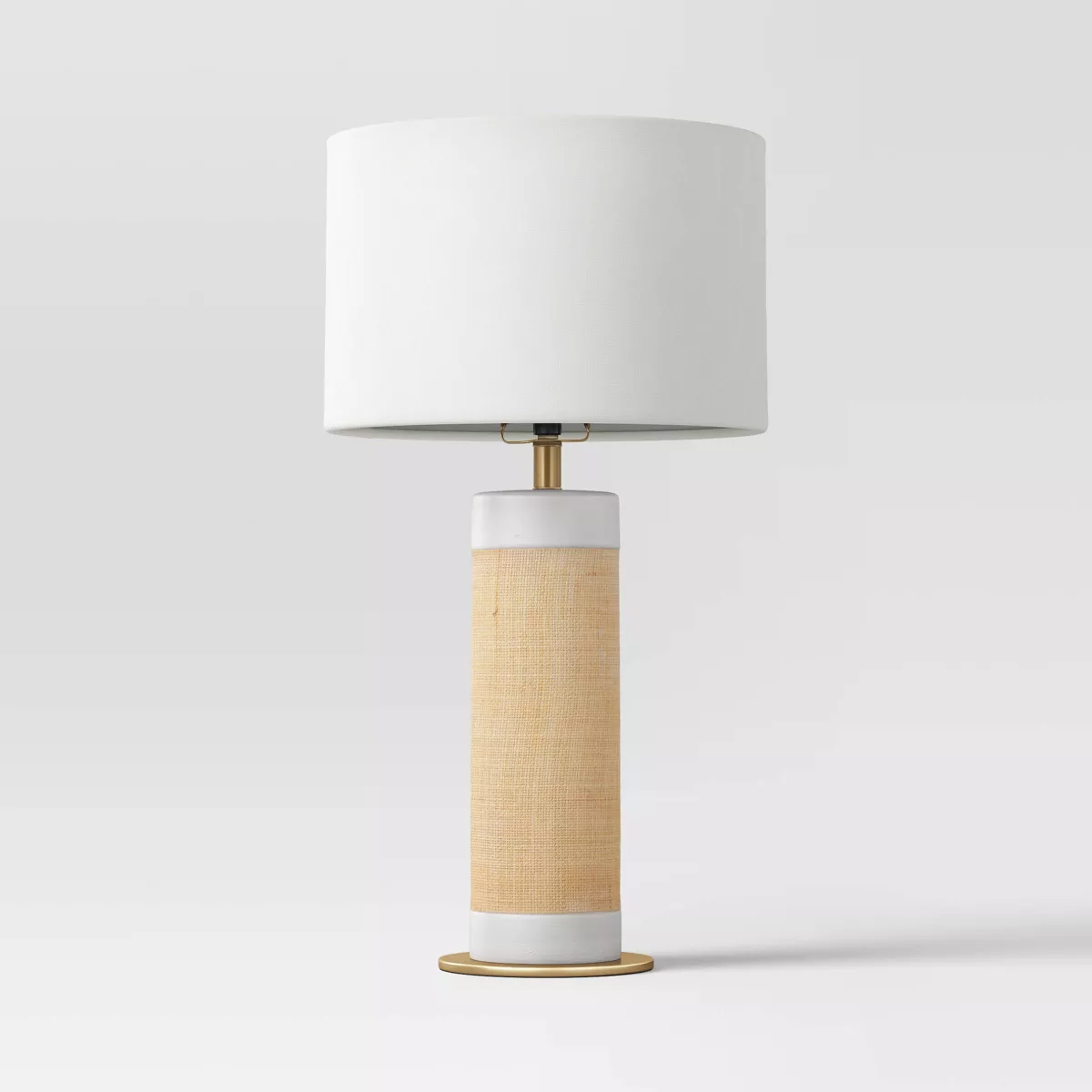 Table lamp with a white shade and woven design base on a light gray background