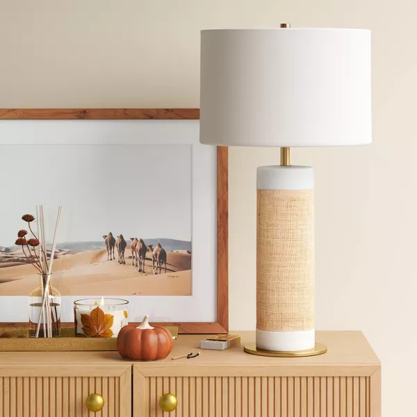 Table lamp with a white shade and woven design base on a light gray background