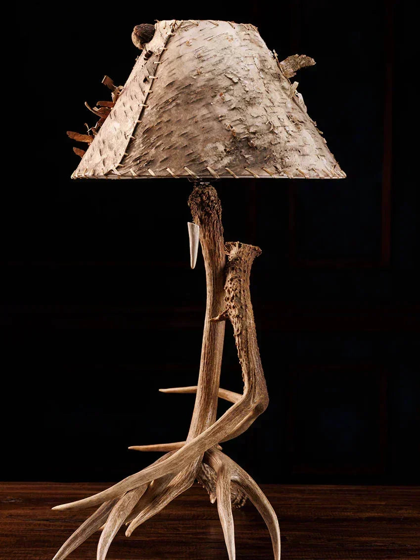 Table lamp with deer antlers and a natural wood shade on a dark background