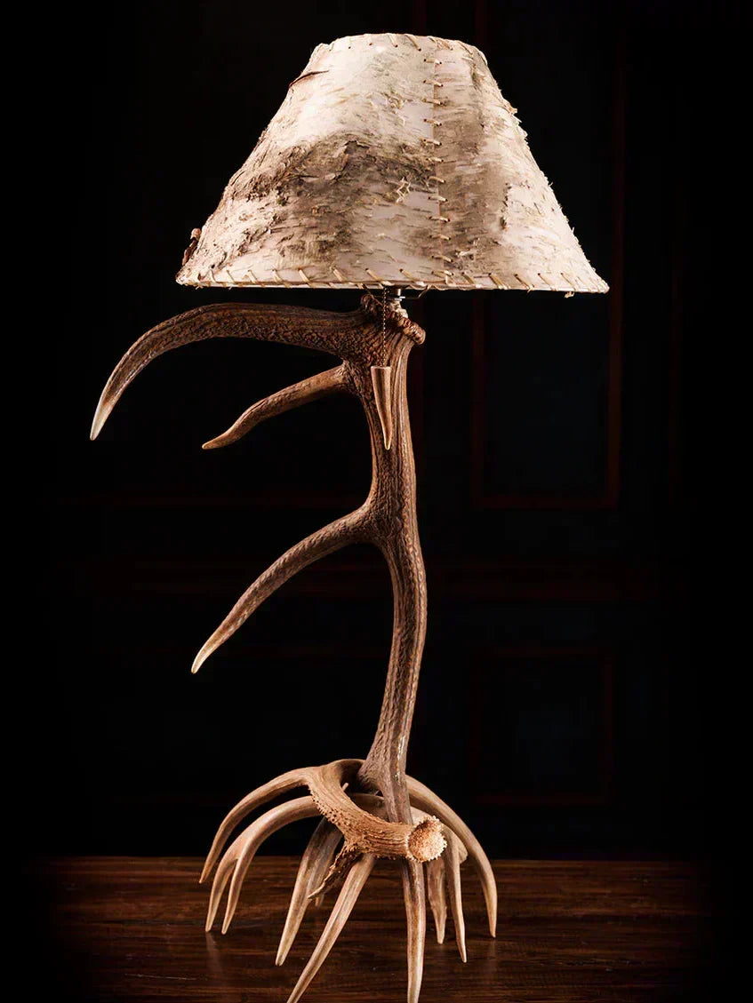 Table lamp with deer antlers and a natural wood shade on a dark background