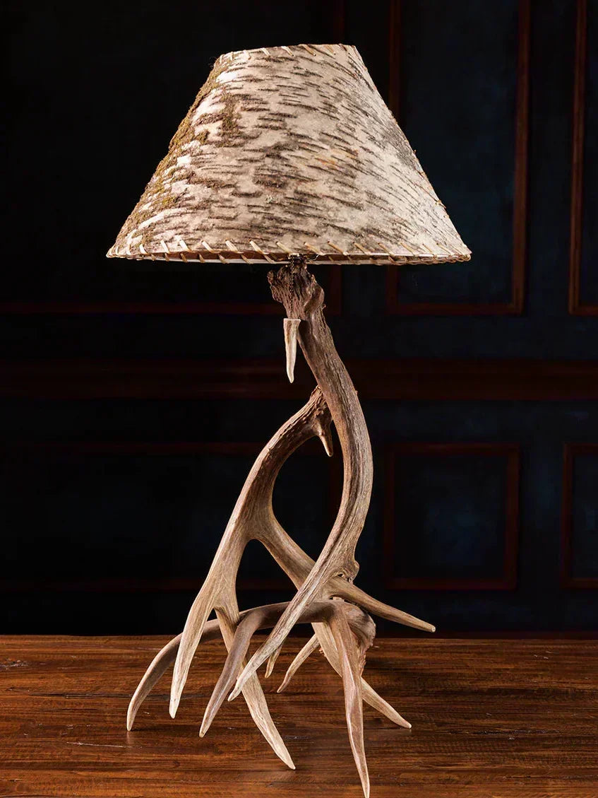 Table lamp with deer antlers and a natural wood shade on a dark background