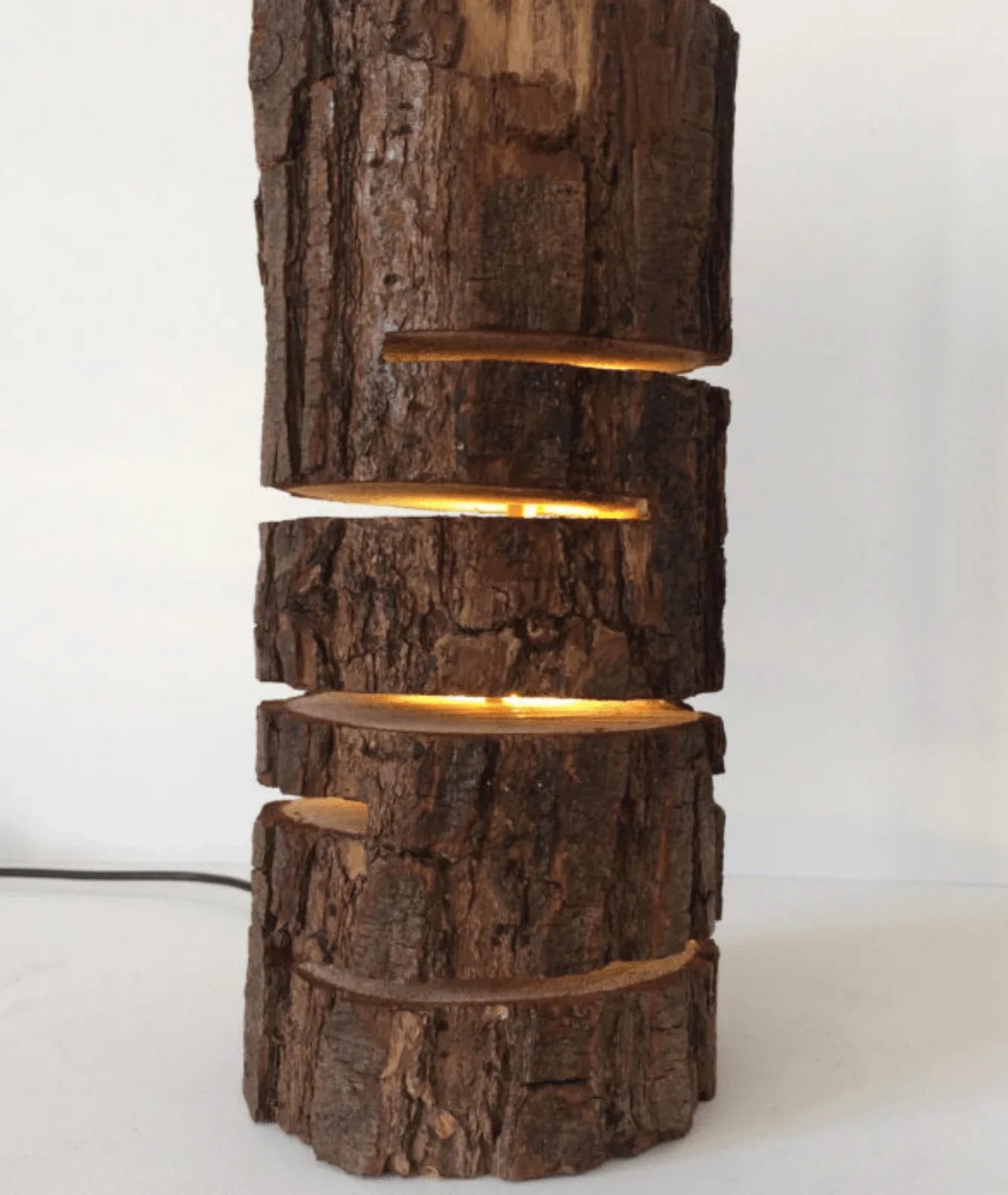 “Glowing Log Wooden Lamp with burnt edges and vertical glowing slits, handcrafted from natural wood with built-in LED for warm rustic ambiance.”