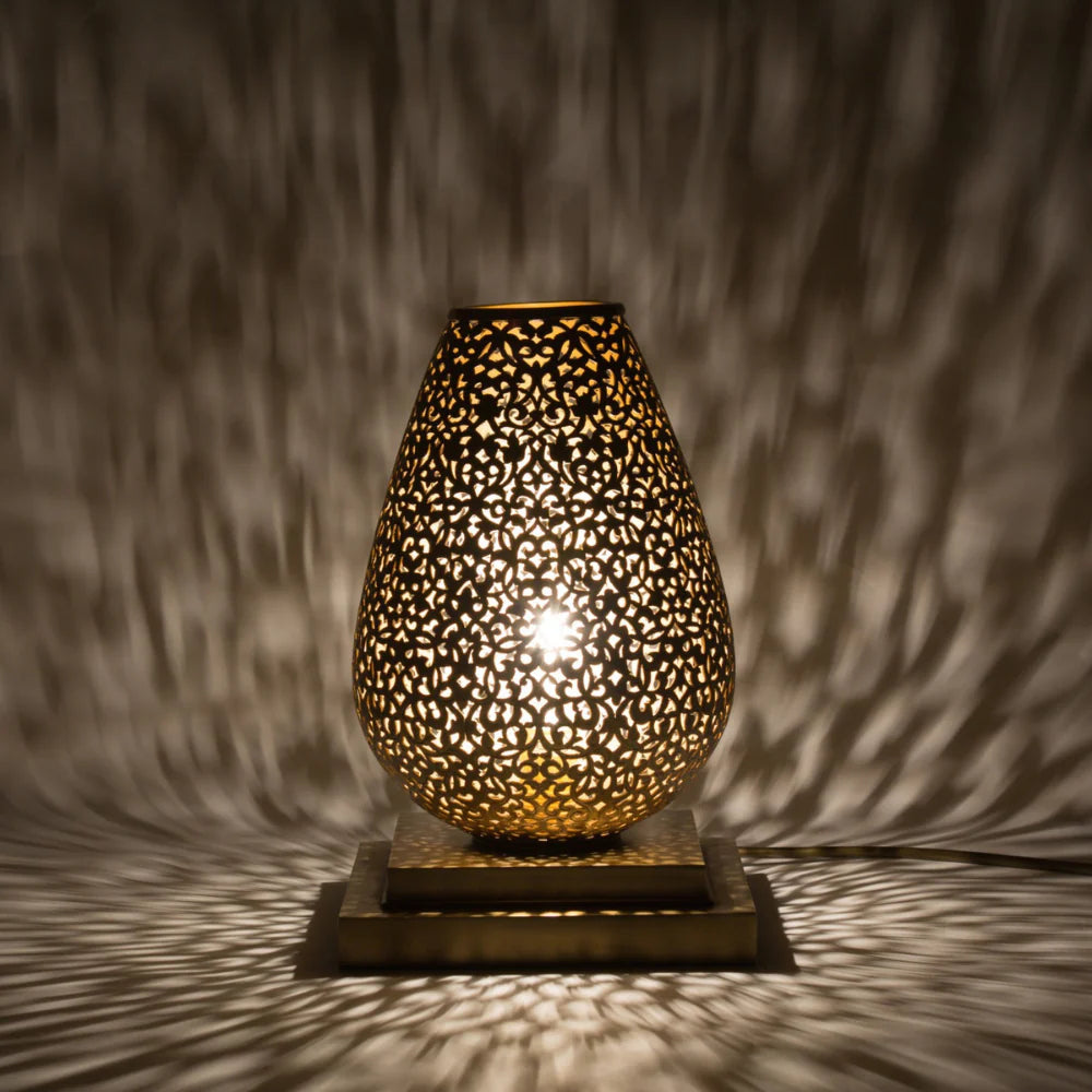 Decorative lamp with intricate design casting shadows on a textured wall.
