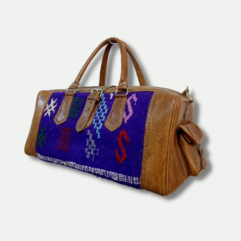 Brown leather bag with colorful patterned flap on a light gray background