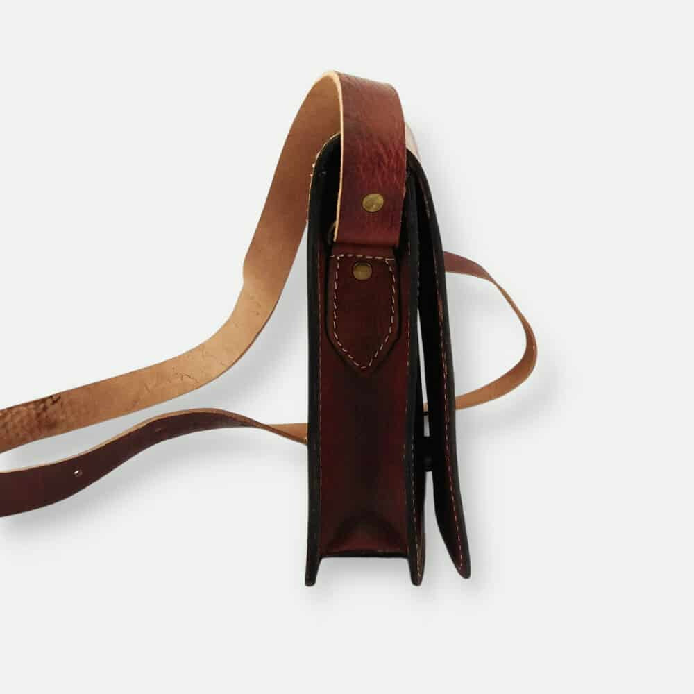 Brown leather bag with strap on a white background