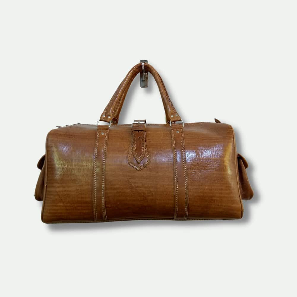 Brown leather duffel bag on a light beige background