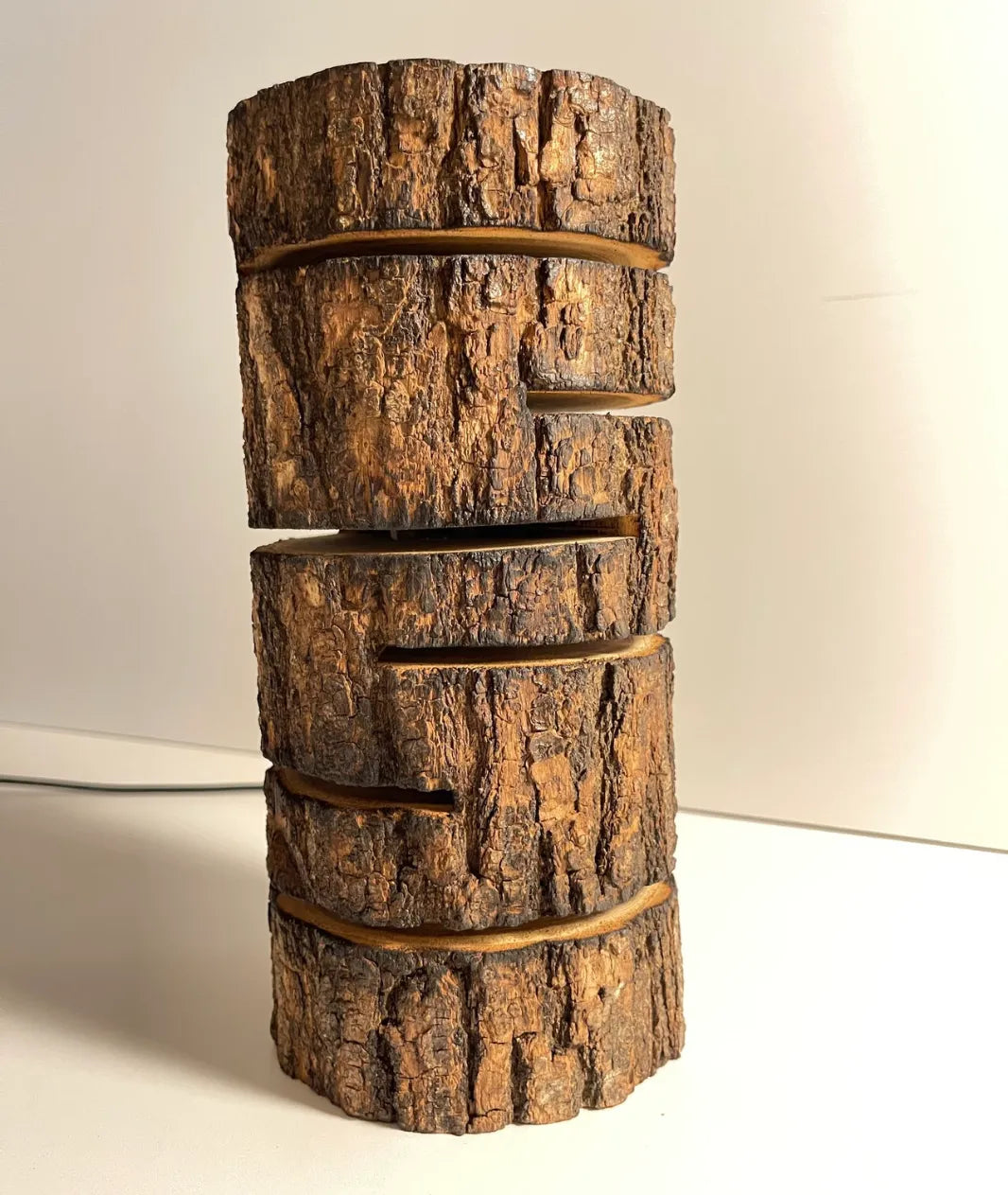 “Glowing Log Wooden Lamp with burnt edges and vertical glowing slits, handcrafted from natural wood with built-in LED for warm rustic ambiance.”