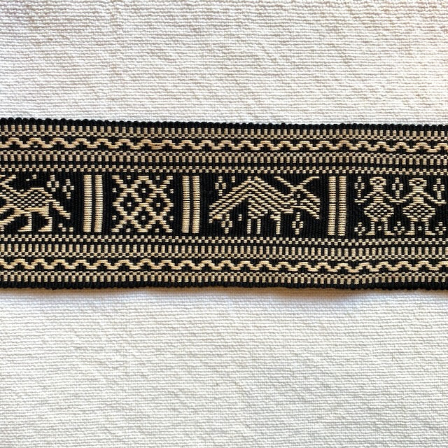 Textile strip with black and beige pattern on a textured white background Style N