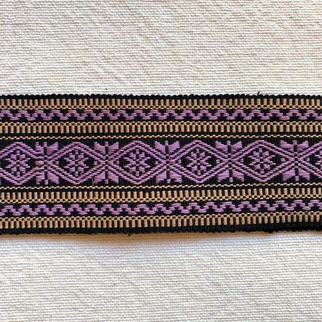 Close-up of woven fabric with purple and brown pattern on a textured background Style P