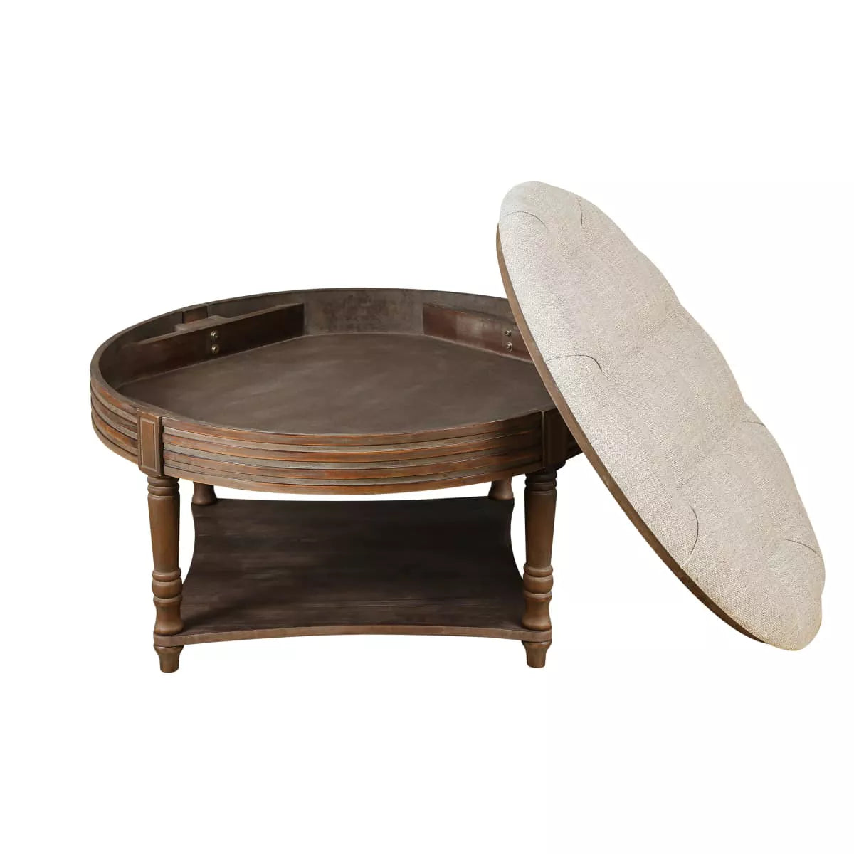 Round wooden coffee table with a beige cushion, vase of green flowers, and books on a patterned rug. beige