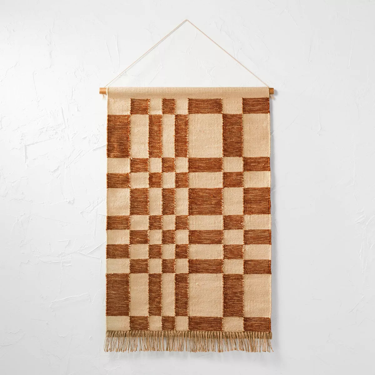 Decorative wall hanging with a checkered pattern above a wooden console table with decorative items.