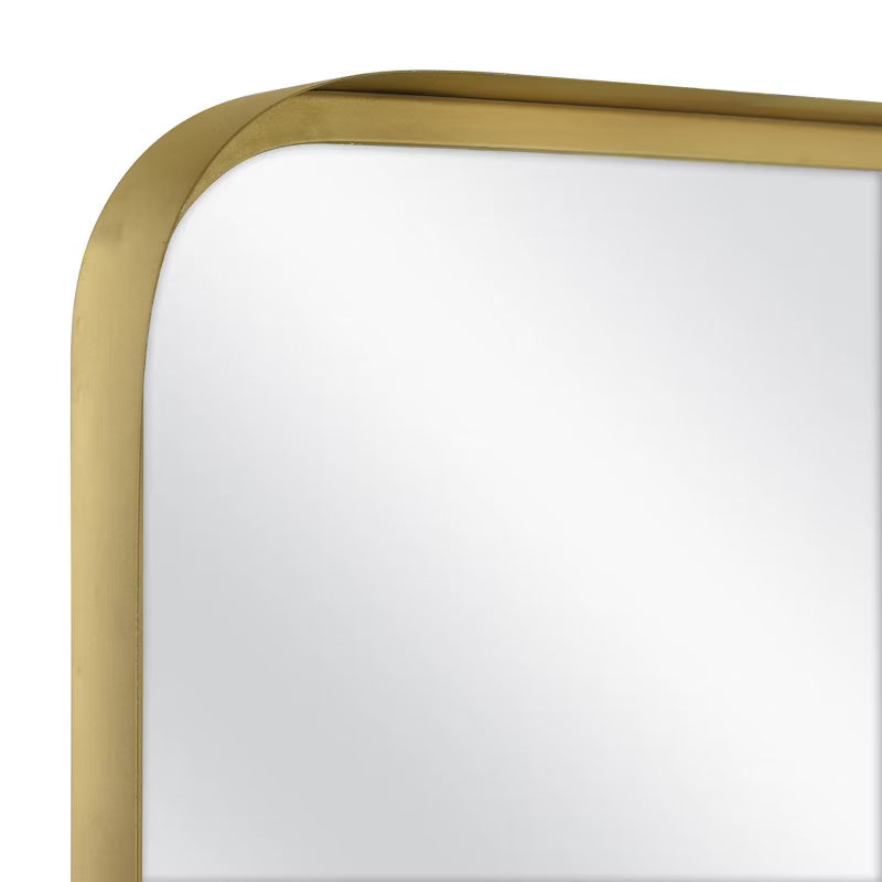 Rectangular mirror with a gold frame on a white wall brass