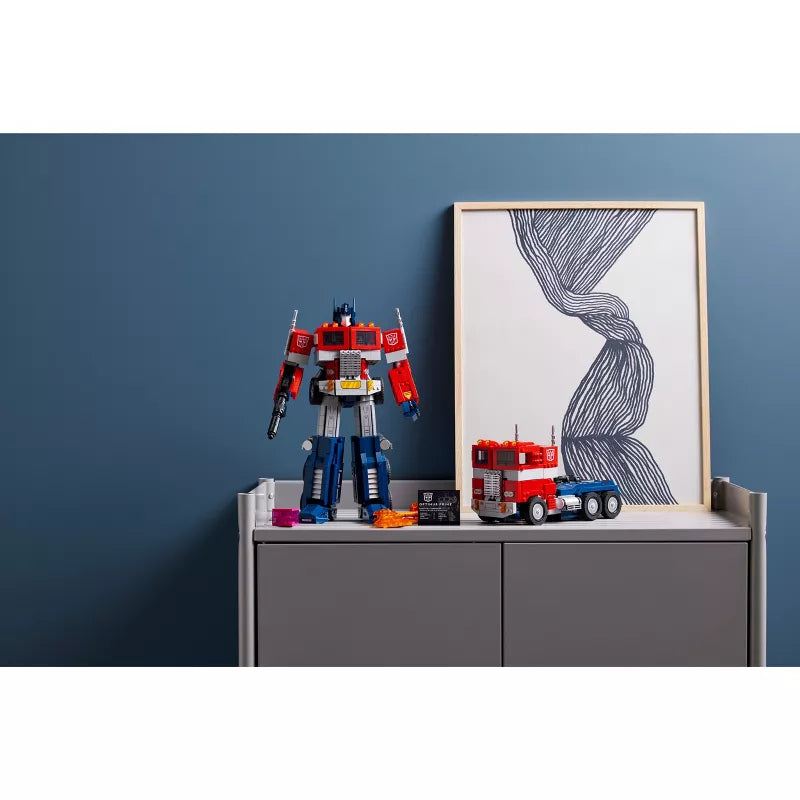 Transformers toy on a shelf with a framed picture against a blue wall