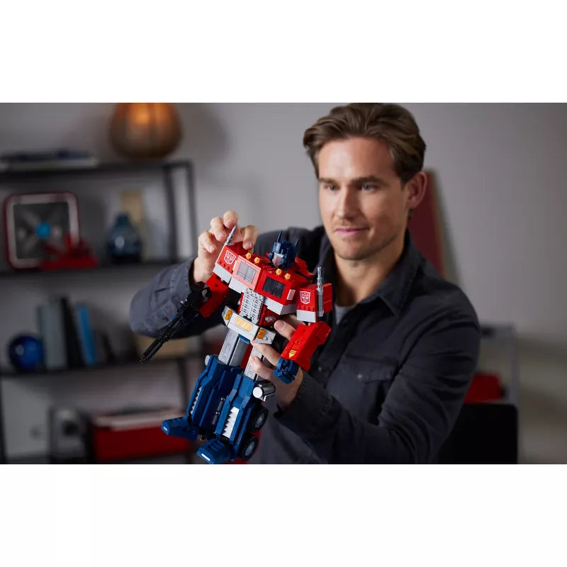 Man holding a robot toy in a room with shelves in the background