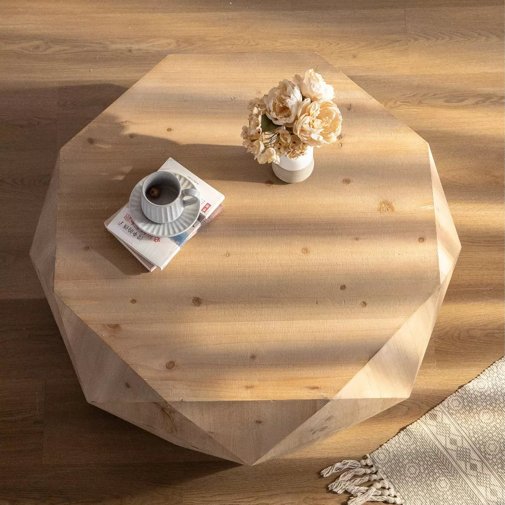 Hexagonal wooden coffee table with a cup, saucer, and flowers on a wooden floor.