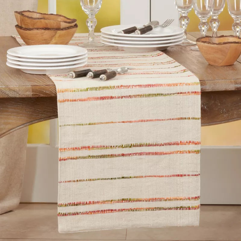 Dining table with a colorful striped table runner, plates, and cutlery.