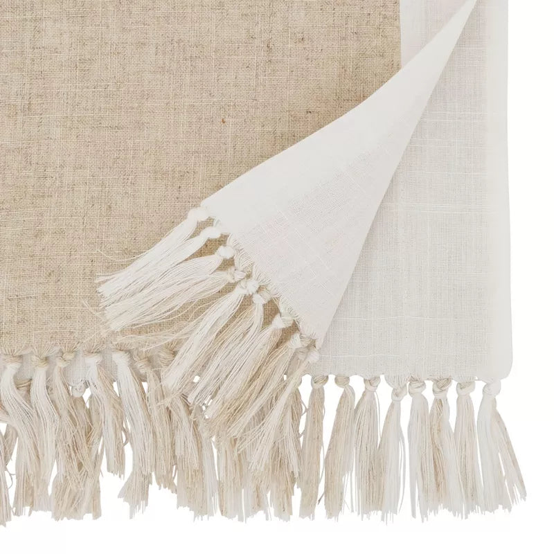 Close-up of a white fabric with tassels on a textured beige background