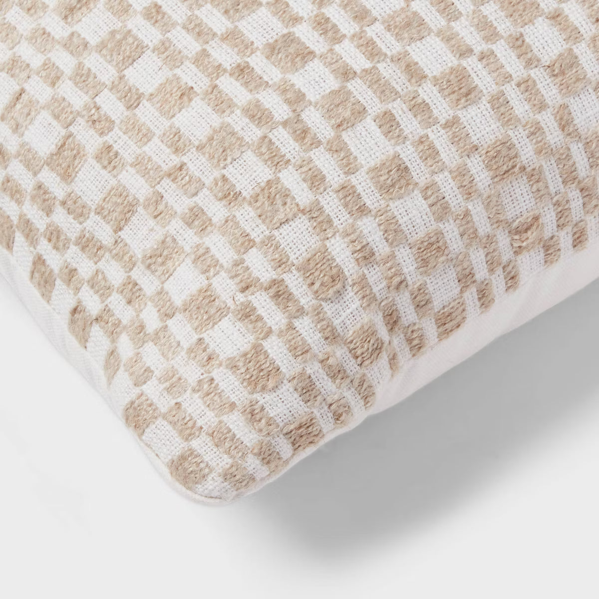 A rectangular throw pillow with a textured woven checkerboard pattern in cream and beige, shown against a light gray background with a soft drop shadow.