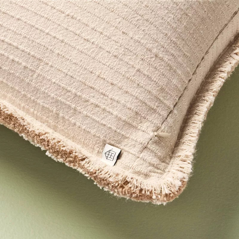 Beige textured pillow with a brand label on a green background Tan