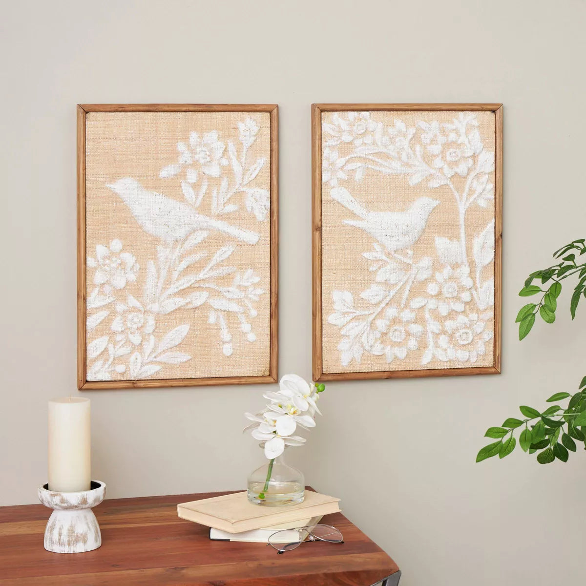 Two framed wall art pieces with bird and floral designs on a neutral wall.
