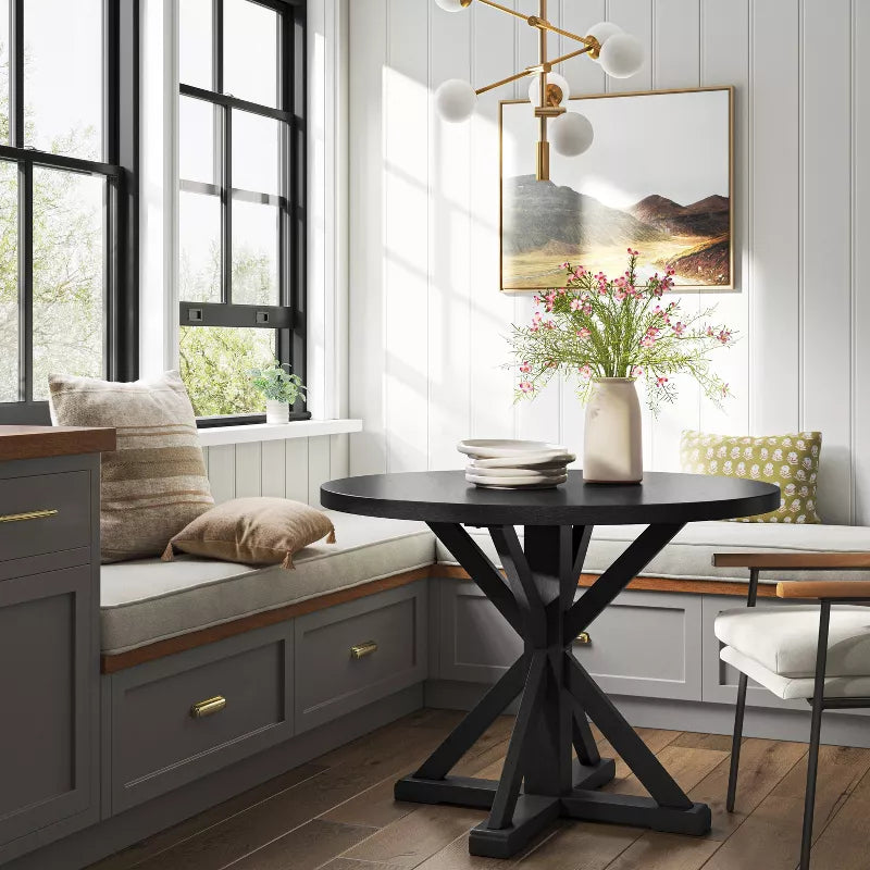 Modern dining room with a black round table, chairs, and decorative elements.
