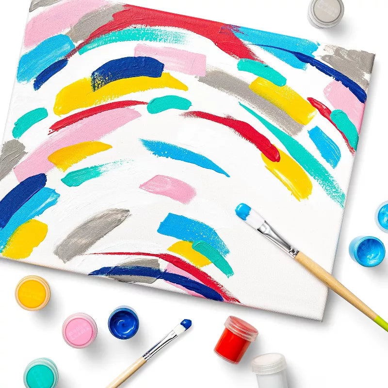 Colorful abstract painting on a white canvas with paintbrushes and containers of paint.