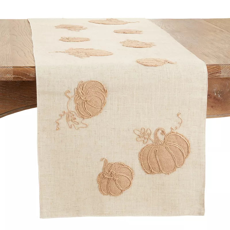 Beige table runner with embroidered pumpkins on a wooden table