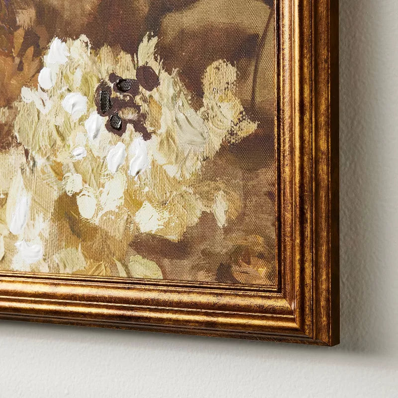 Framed floral painting with a gold frame on a neutral wall.