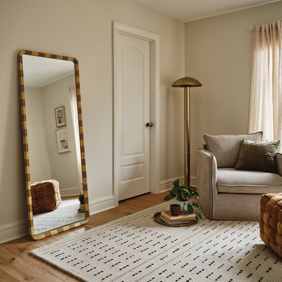 A mirror with a rounded corner and a checkered frame in alternating light and dark brown colored wood.
